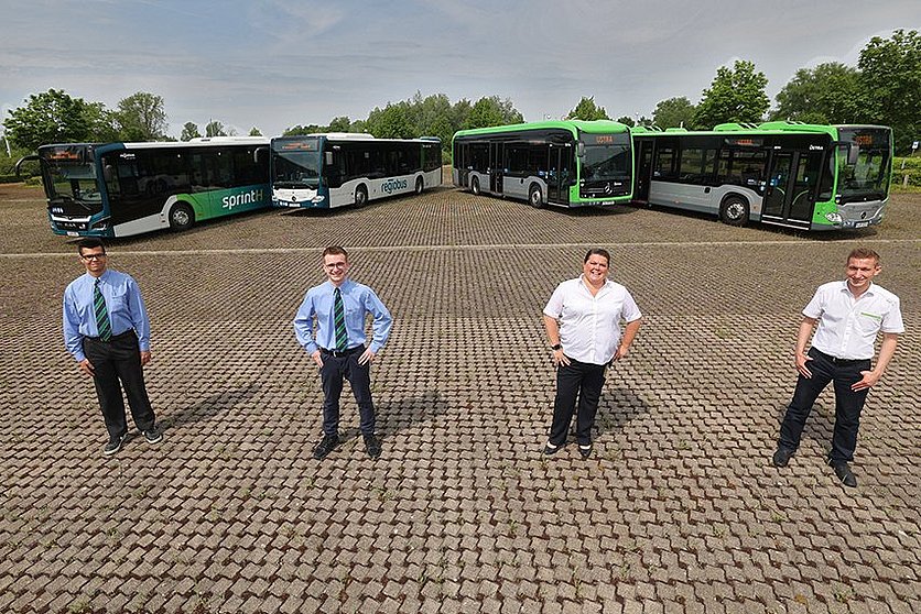 Vier Busse von regiobus und ÜSTRA stehen in Frontalansicht aufgefächert nebeneinander, davor stehen drei Busfahrer und eine Busfahrerin. 