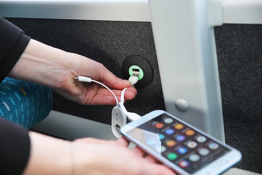 Fahrgast steckt in einem sprintH Bus ein Handy in die USB-Buchse.