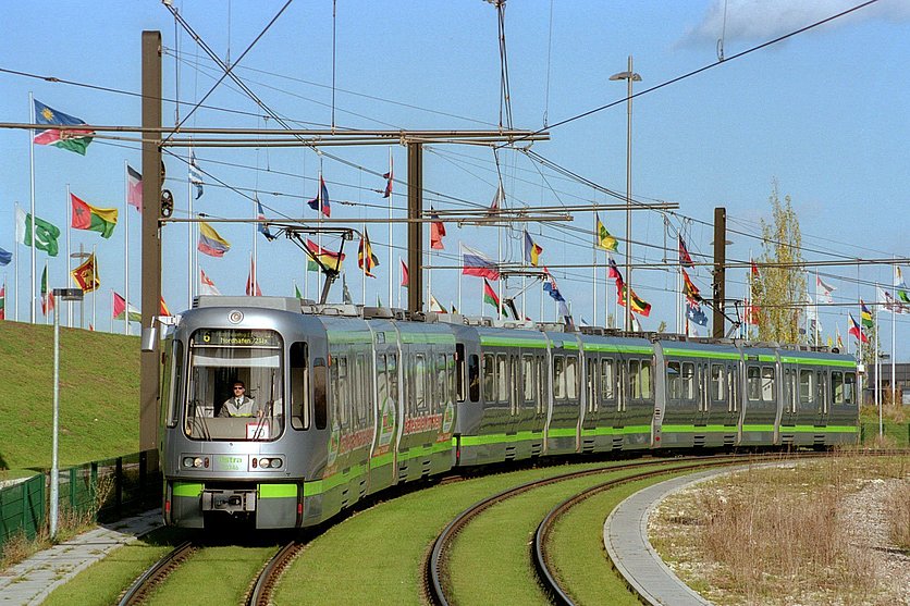 Picture of a TW 2000 on the move. In the background and on the side are flags of the Expo.