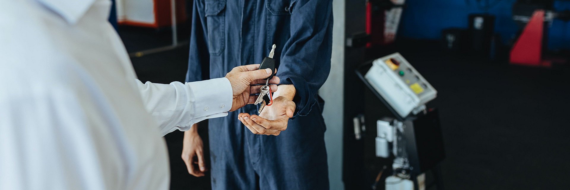 Eine Person übergibt einen Schlüssel an einen Werkstattmitarbeiter