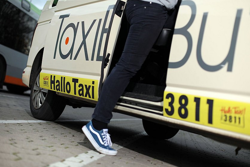 Detailbild von einer Person, die in einen Taxibus einsteigt.