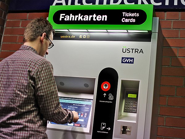 Ein Mann steht am Fahrkartenautomat einer unterirdischen Haltestelle.