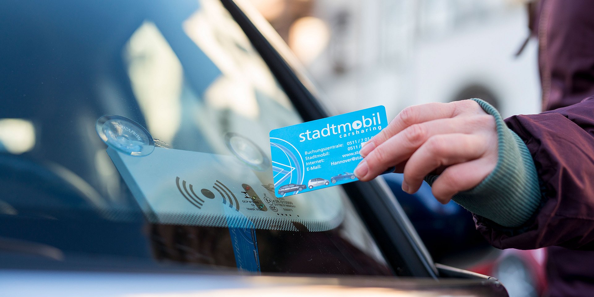 Detail image of an access card held in front of the windshield of a stadtmobil car