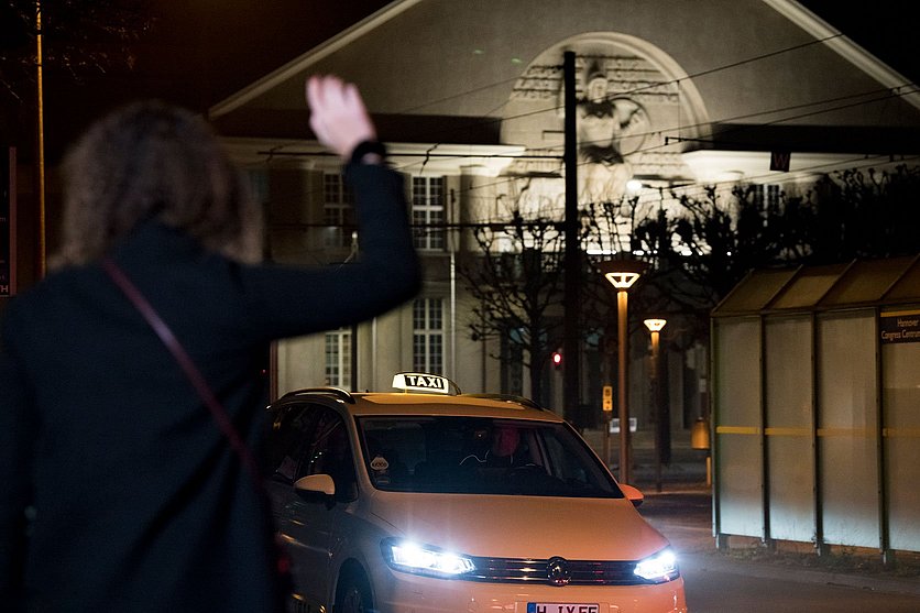 Bild von einer Frau, die nachts ein Taxi heranwinkt. 