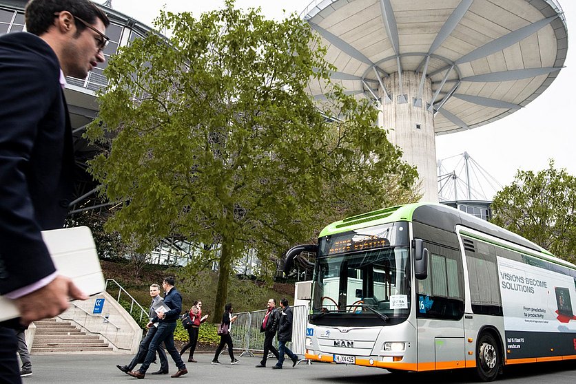 Bild vom Deutschen Messegelände in Hannover. Auf der linken Seite ist ein Mann zu sehen und rechts im Bild ein ÜSTRA Bus