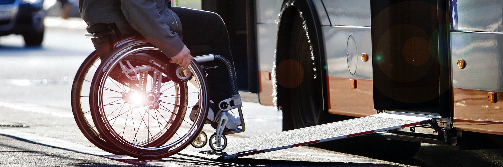 Picture of a person with wheelchair on a ramp entering a bus